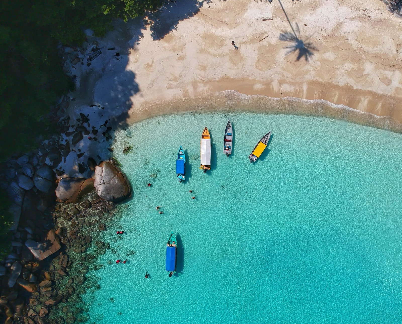 Vista de cima da Ilhas Perhentian, Malásia com mar azul claro, quatro barcos no mar e areias claras.