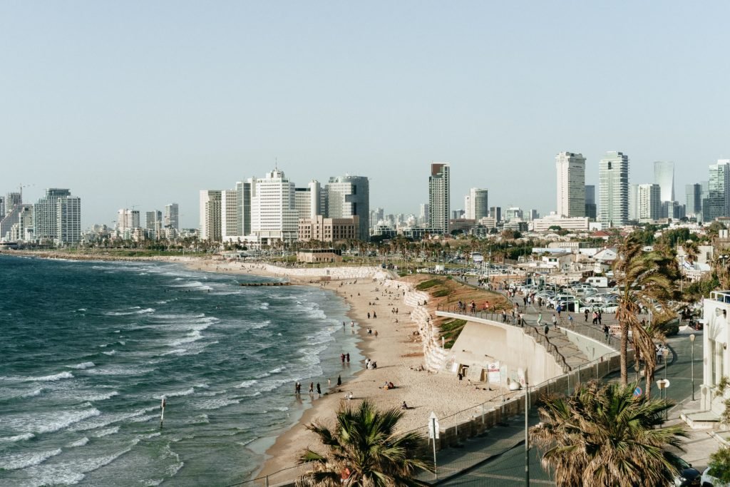 Praia com pessoas e cidade ao fundo em Tel Aviv, capital de Israel