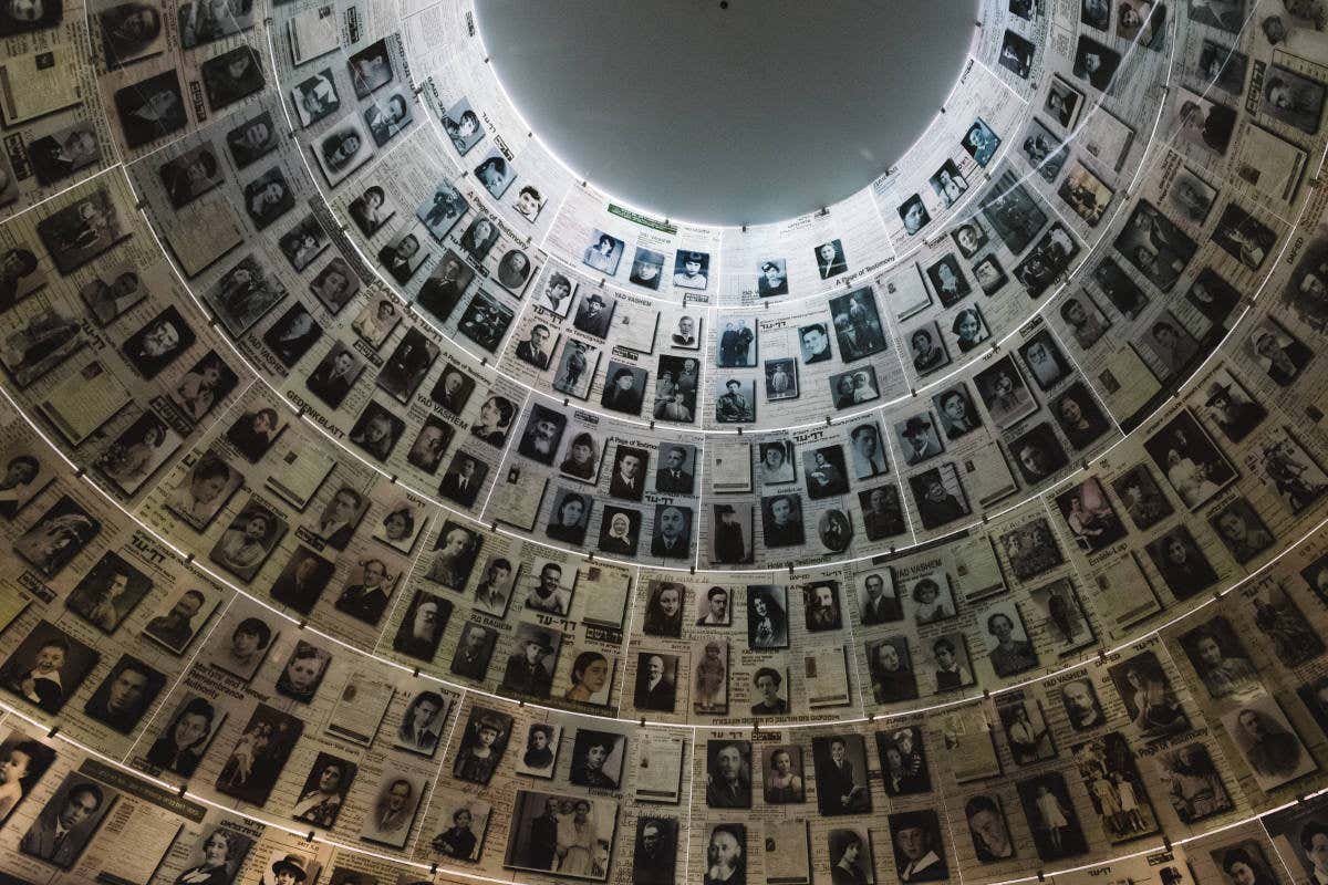 Um teto abobadado coberto com fotografias de vítimas do Holocausto em preto e branco de pessoas, dispostas em um padrão circular com iluminação superior. Está no Museu do Holocausto, representando o post de o que fazer em Israel.