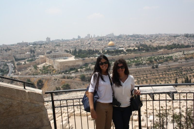 Duas mulheres adultas encostadas em uma grade de ferro com paisagem para o Muro das Lamentações, em Jerusalém. Ilustra o que fazer em Israel.