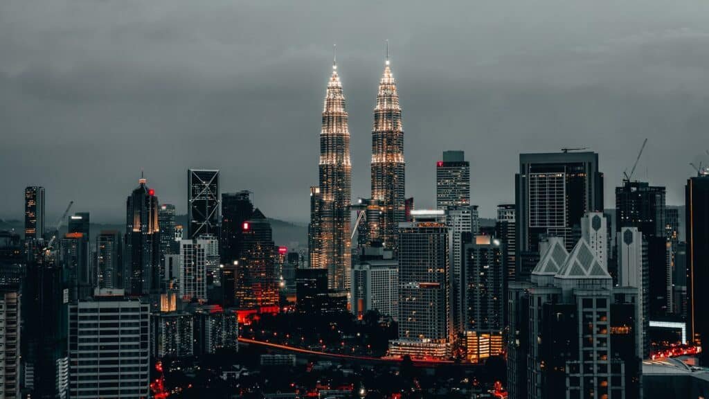 Horizonte da cidade ao anoitecer, com as Torres Petronas iluminadas entre os arranha-céus ao redor, em Kuala Lumpur, Malásia. Representa eSIM Malásia.